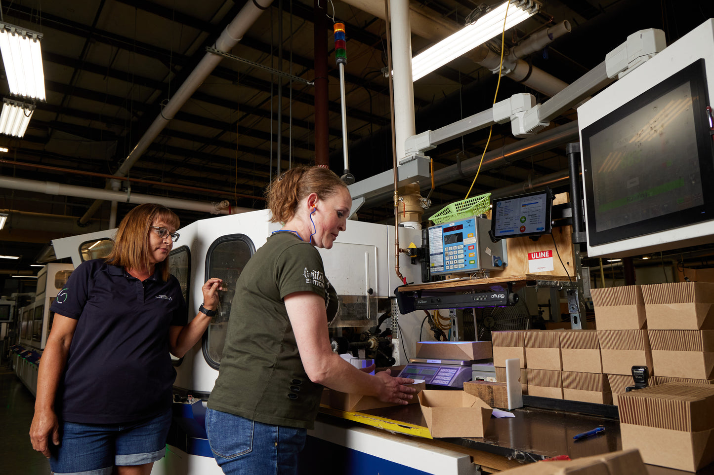 Two JBM employees working at a machine on the manufacturing floor. 