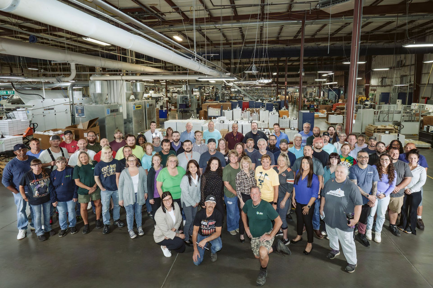 JBM Packaging employees posing for a group photo in the  manufacturing room.