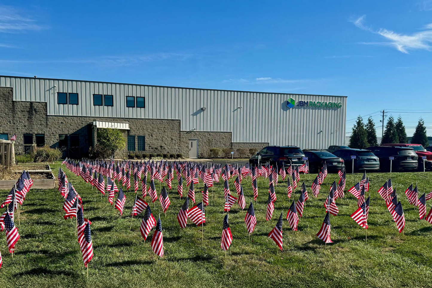 Front of JBM Packaging building with tons of American flags lining the front lawn. 